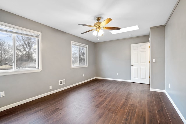 unfurnished room with a skylight, a healthy amount of sunlight, and dark hardwood / wood-style floors