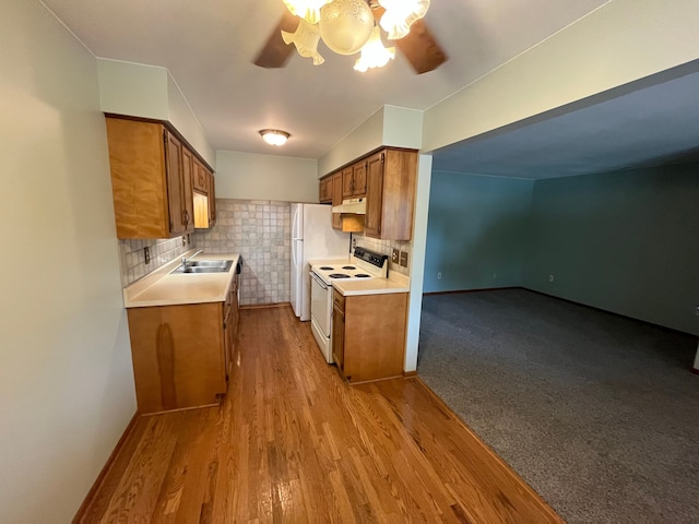 kitchen with tasteful backsplash, white appliances, ceiling fan, sink, and light hardwood / wood-style flooring