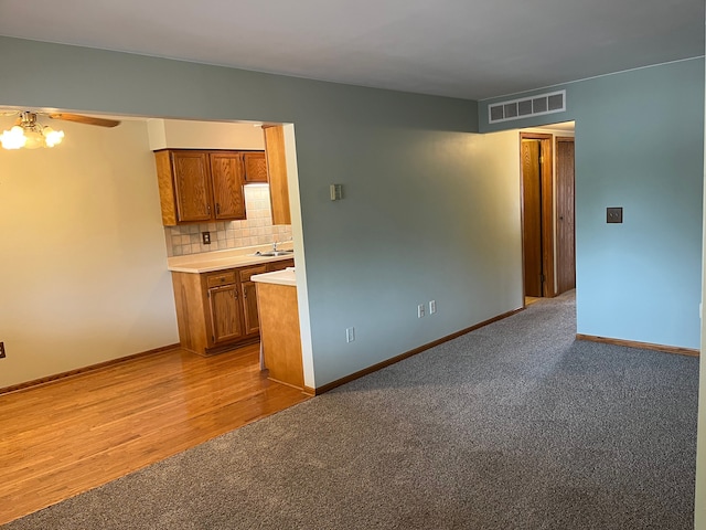 unfurnished living room with ceiling fan, sink, and light colored carpet