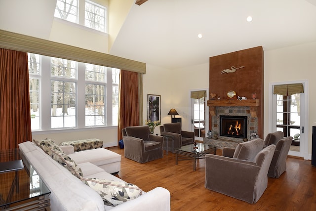 living area with a fireplace, a high ceiling, wood finished floors, and recessed lighting