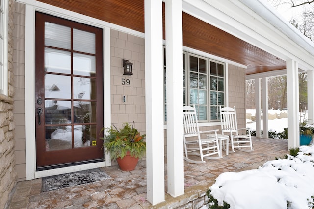 snow covered property entrance with a porch