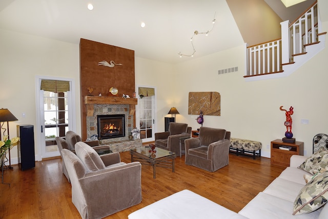 living room with a high ceiling, a fireplace, wood finished floors, and visible vents