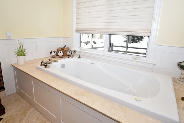 full bathroom with a wainscoted wall and a bath