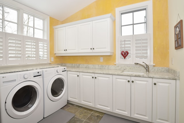 clothes washing area featuring a sink, cabinet space, plenty of natural light, and washer and dryer