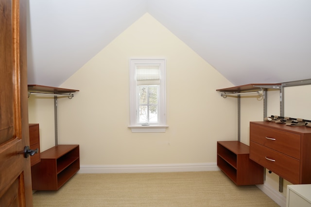 walk in closet with light carpet and lofted ceiling