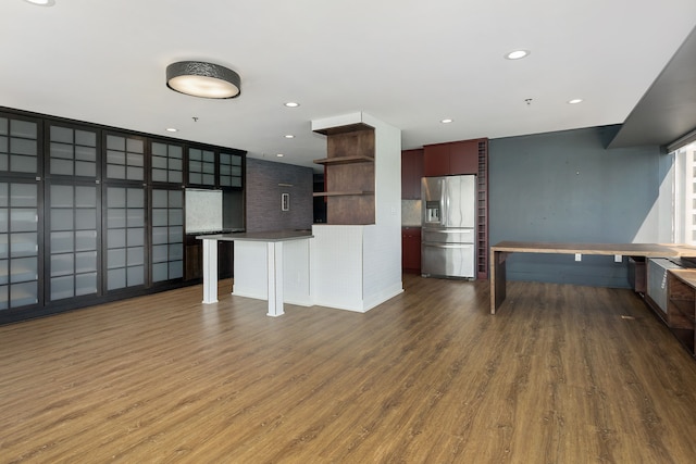 kitchen featuring dark hardwood / wood-style floors, stainless steel refrigerator with ice dispenser, backsplash, a breakfast bar area, and a kitchen island