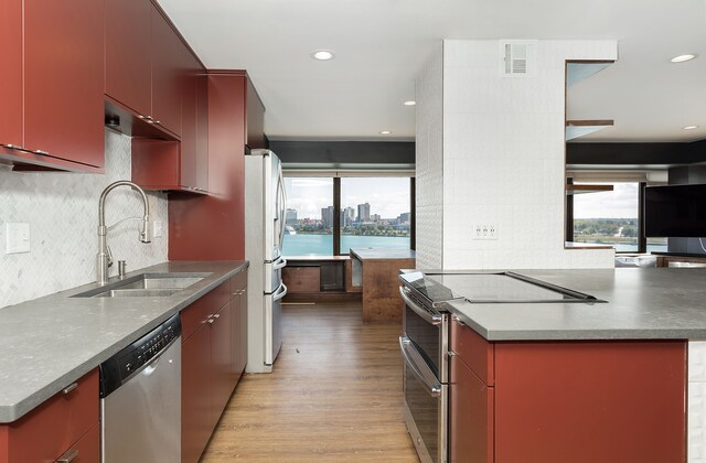 kitchen with tasteful backsplash, sink, stainless steel appliances, and light hardwood / wood-style floors