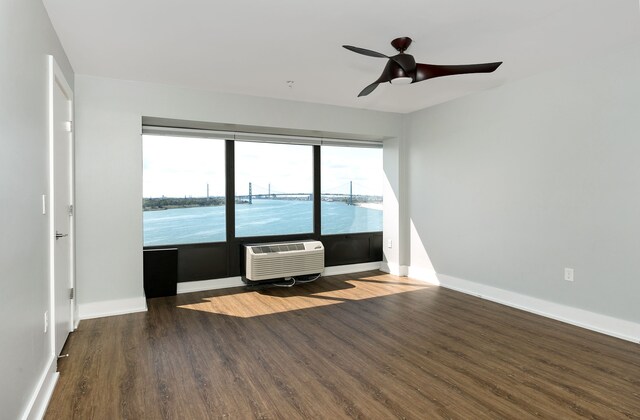 empty room with an AC wall unit, ceiling fan, and dark wood-type flooring