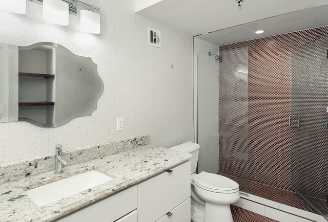 bathroom with baseboard heating, vanity, an enclosed shower, and toilet