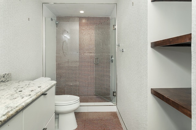 bathroom featuring tile patterned flooring, vanity, toilet, and a tile shower