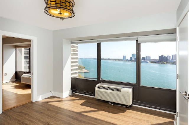 interior space with hardwood / wood-style floors, a water view, and a wall unit AC