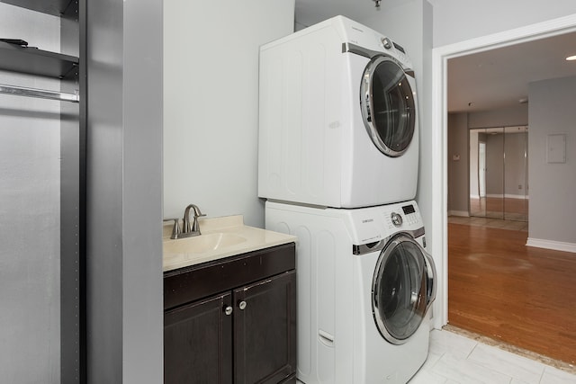 washroom featuring cabinets, light tile patterned floors, stacked washer and clothes dryer, and sink