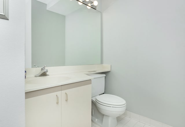 bathroom with toilet, vanity, and tile patterned floors