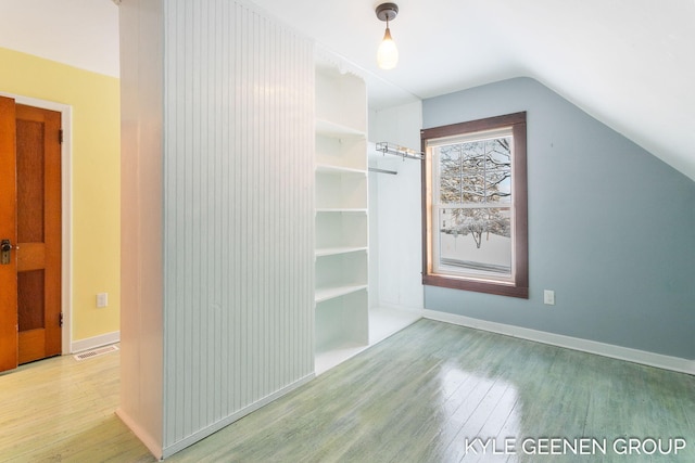 bonus room with light wood-type flooring and vaulted ceiling