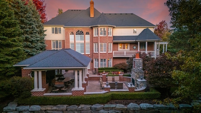 back house at dusk featuring a fireplace and a patio area