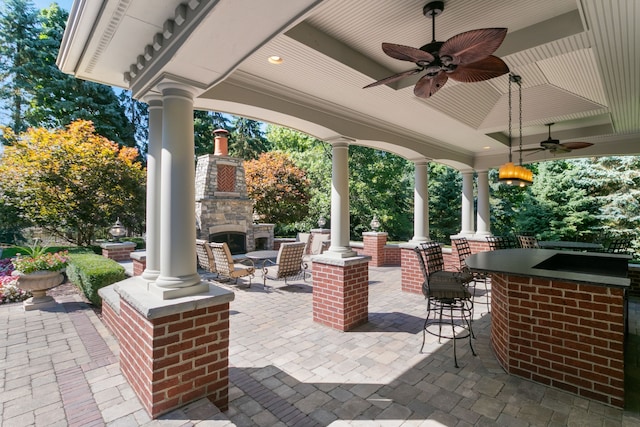 view of patio / terrace with an outdoor stone fireplace, an outdoor bar, and ceiling fan