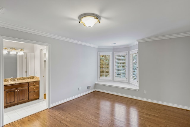 empty room with light wood-type flooring, ornamental molding, and sink