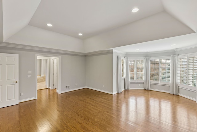 unfurnished living room featuring a tray ceiling, crown molding, and hardwood / wood-style floors