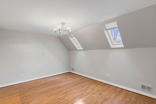 bonus room with a notable chandelier, light hardwood / wood-style floors, and lofted ceiling with skylight