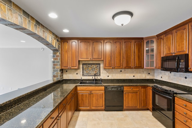 kitchen featuring sink, tasteful backsplash, dark stone countertops, and black appliances