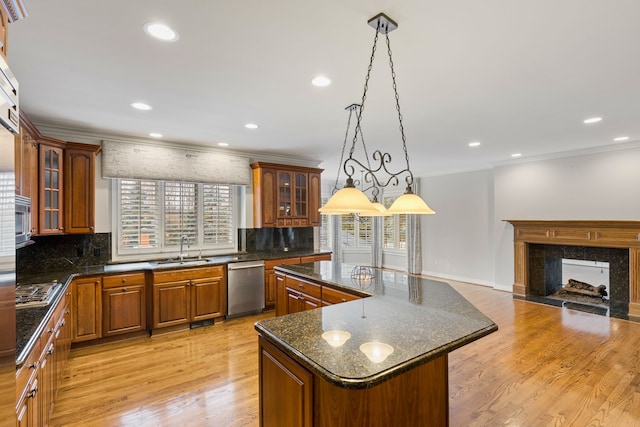 kitchen with sink, stainless steel appliances, pendant lighting, a fireplace, and a kitchen island