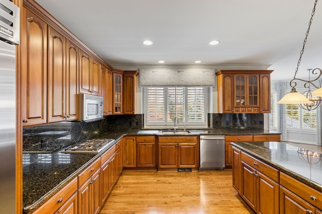 kitchen with sink, hanging light fixtures, light wood-type flooring, tasteful backsplash, and stainless steel appliances