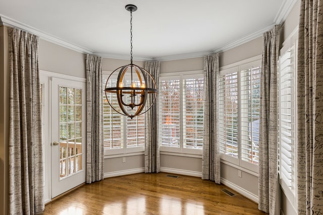 unfurnished dining area featuring hardwood / wood-style floors, crown molding, and an inviting chandelier