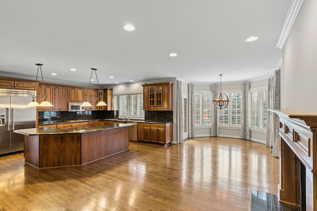 kitchen featuring pendant lighting, a healthy amount of sunlight, ornamental molding, appliances with stainless steel finishes, and a kitchen island