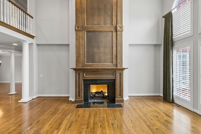 unfurnished living room with decorative columns, light hardwood / wood-style flooring, and crown molding