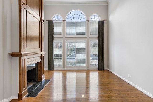 unfurnished living room with hardwood / wood-style floors, crown molding, and a high end fireplace