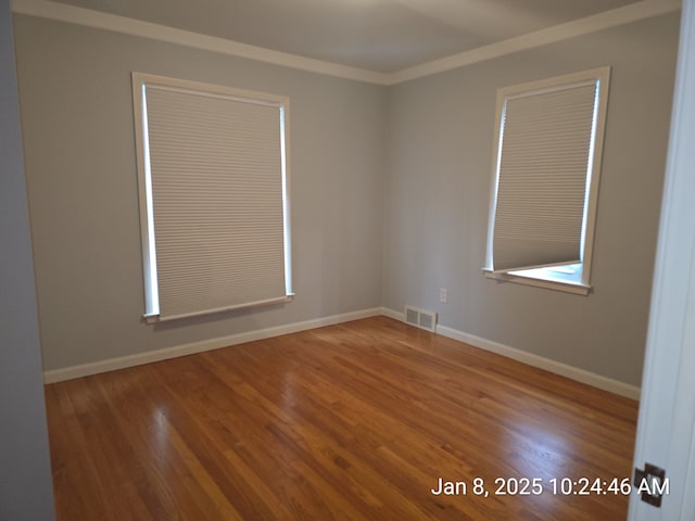 spare room featuring wood-type flooring and ornamental molding