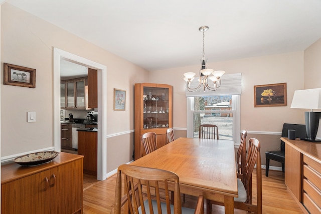 dining room with light wood-type flooring and a notable chandelier