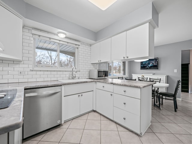 kitchen with white cabinets, appliances with stainless steel finishes, kitchen peninsula, and sink