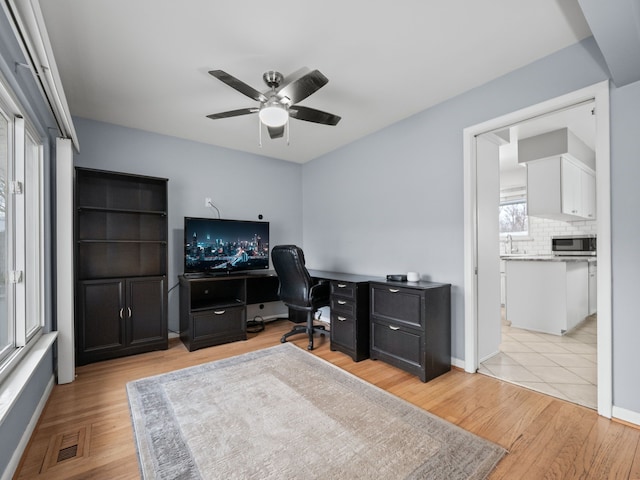 office space featuring ceiling fan, light hardwood / wood-style floors, and sink