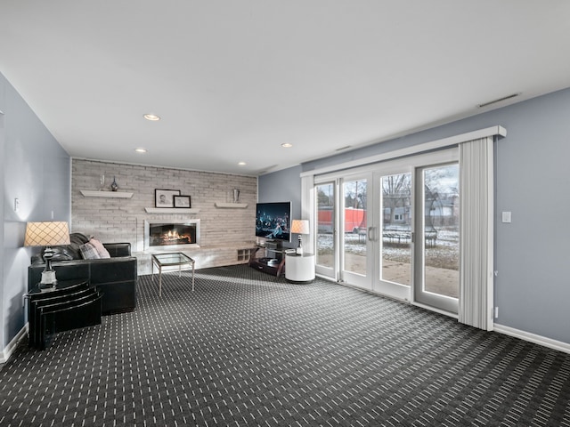 living room with a fireplace, brick wall, and dark colored carpet