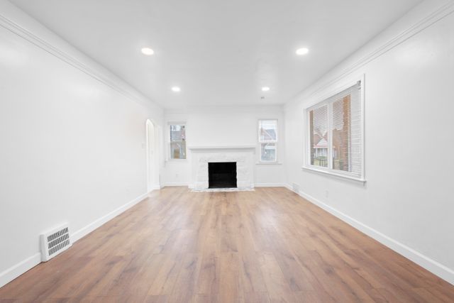 unfurnished living room featuring hardwood / wood-style floors and ornamental molding