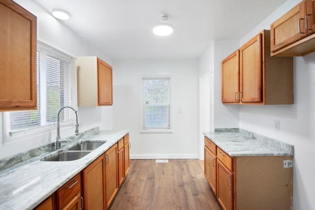 kitchen featuring light stone counters, sink, and light hardwood / wood-style flooring