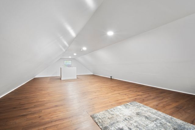 additional living space with vaulted ceiling and hardwood / wood-style flooring