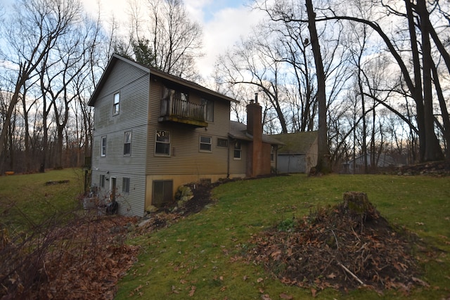 rear view of property featuring a balcony and a yard