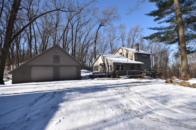 snow covered property with an outdoor structure and a garage