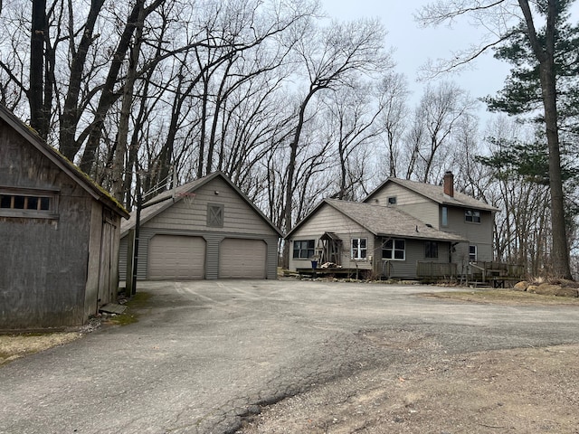 9417 Mabley Hill Rd, Fenton, MI 48430 - view of front of house featuring a detached garage, an outdoor structure, a wooden deck, and a chimney