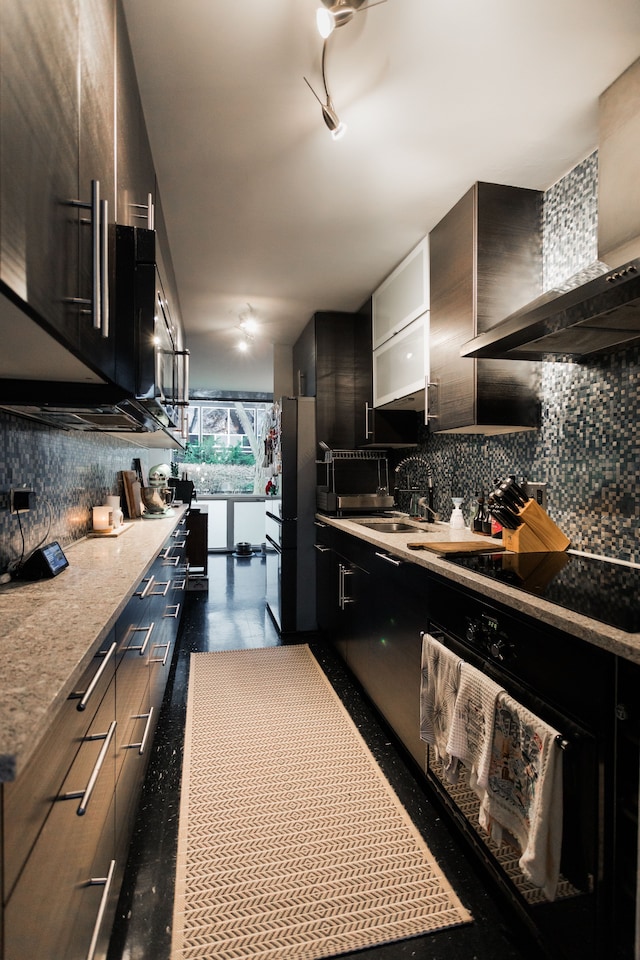 kitchen featuring stainless steel fridge, black electric stovetop, tasteful backsplash, wall chimney exhaust hood, and sink