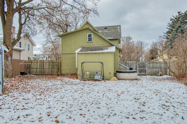 snow covered back of property with a jacuzzi