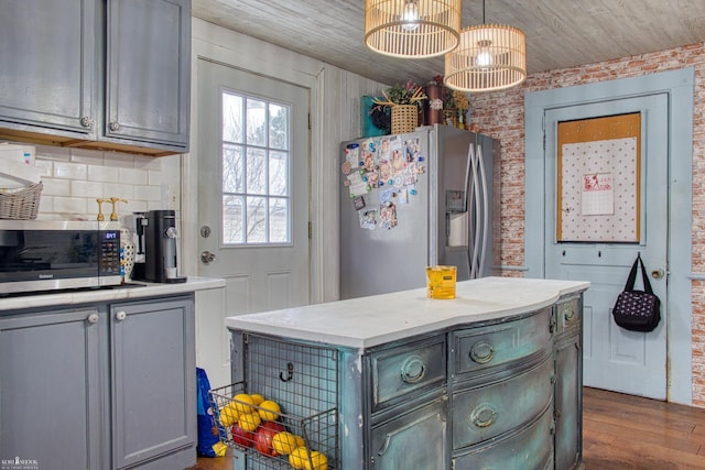 kitchen featuring gray cabinetry, wooden ceiling, hanging light fixtures, stainless steel appliances, and brick wall