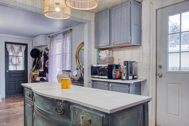 kitchen featuring gray cabinetry, dark hardwood / wood-style flooring, hanging light fixtures, and tasteful backsplash