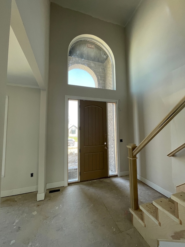entryway with baseboards, a towering ceiling, and stairway