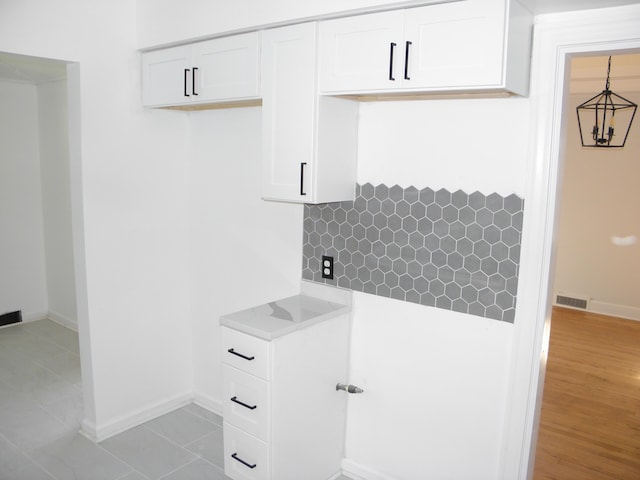 clothes washing area featuring light tile patterned floors and an inviting chandelier