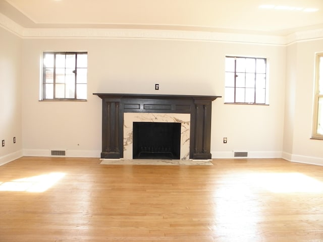 unfurnished living room featuring crown molding, a fireplace, and light wood-type flooring