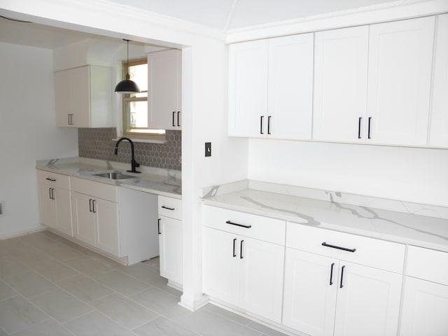 kitchen featuring light stone countertops, pendant lighting, white cabinetry, and sink