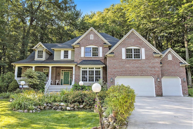 view of front of house featuring covered porch, a garage, and a front yard